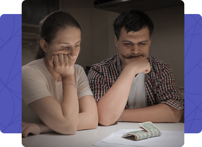 Couple sitting at a table looking stressed at a small amount of cash, concerned about tax debt